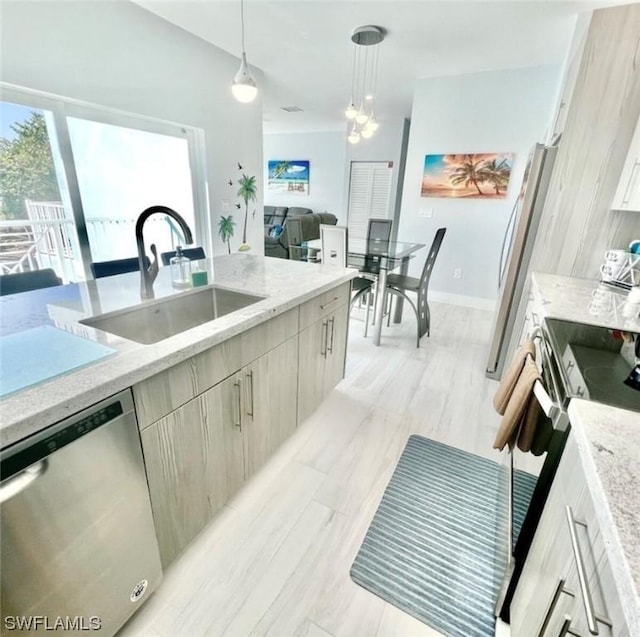 kitchen with stainless steel appliances, hanging light fixtures, a sink, and light stone countertops