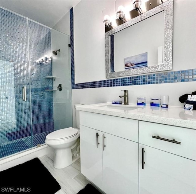 bathroom featuring tile walls, decorative backsplash, toilet, a stall shower, and vanity