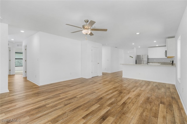 unfurnished living room with ceiling fan and light hardwood / wood-style flooring