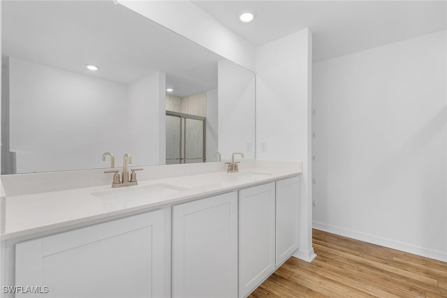 bathroom featuring vanity, wood-type flooring, and a shower with shower door