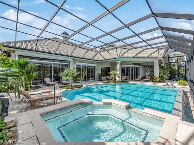 view of pool with glass enclosure, an in ground hot tub, and a patio