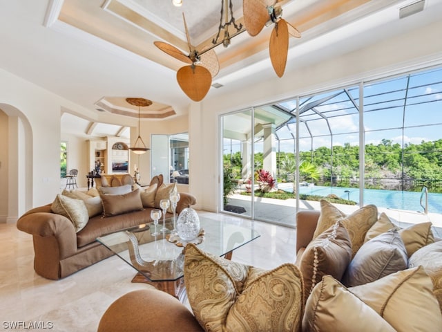 tiled living room featuring a raised ceiling, ceiling fan, and ornamental molding