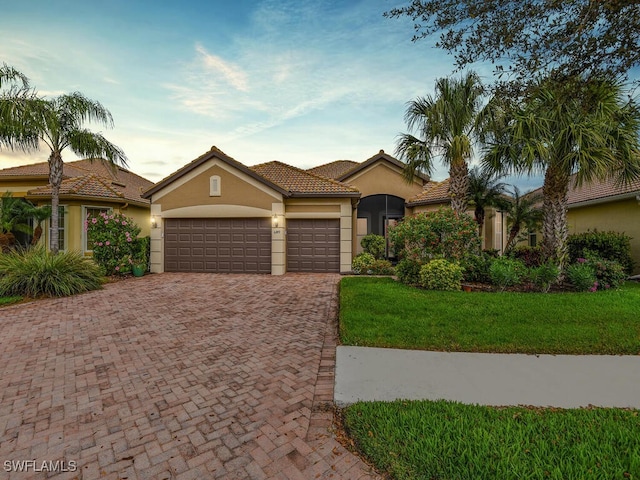 mediterranean / spanish-style home featuring a yard and a garage