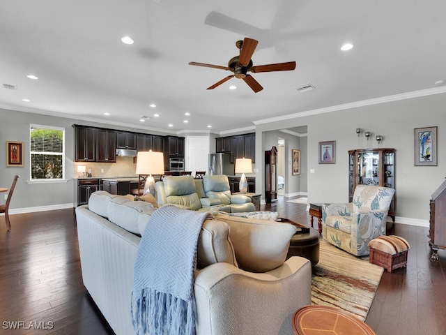 living room with dark wood-type flooring, ceiling fan, and crown molding