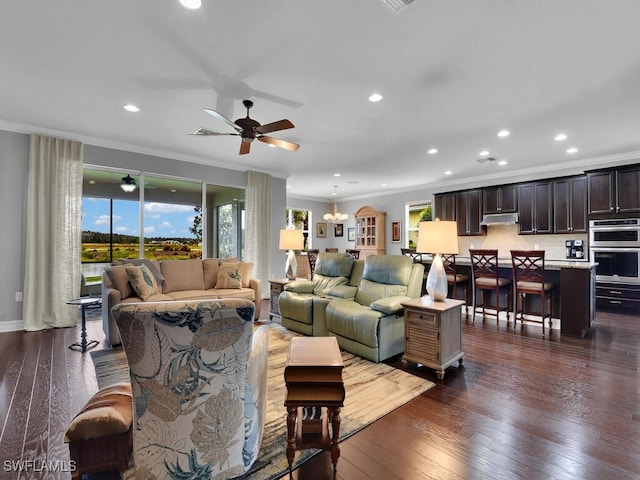 living room with crown molding, ceiling fan with notable chandelier, dark wood-type flooring, and a wealth of natural light