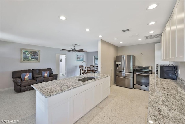 kitchen with stainless steel appliances, sink, white cabinets, and light stone counters