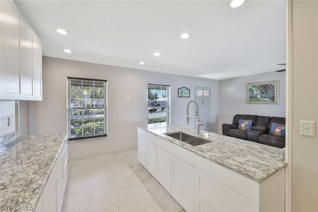 kitchen with light stone counters, sink, and white cabinets