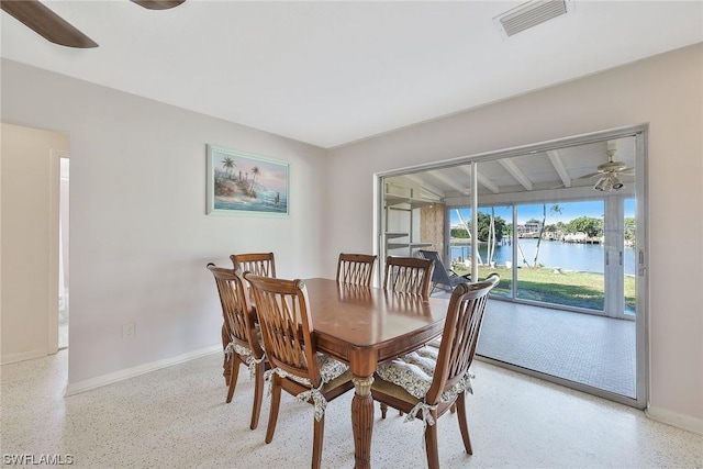 dining area with a water view and ceiling fan