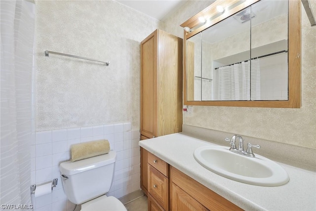 bathroom with tile walls, vanity, and toilet