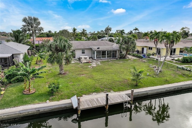 back of property featuring a water view, a yard, and a sunroom