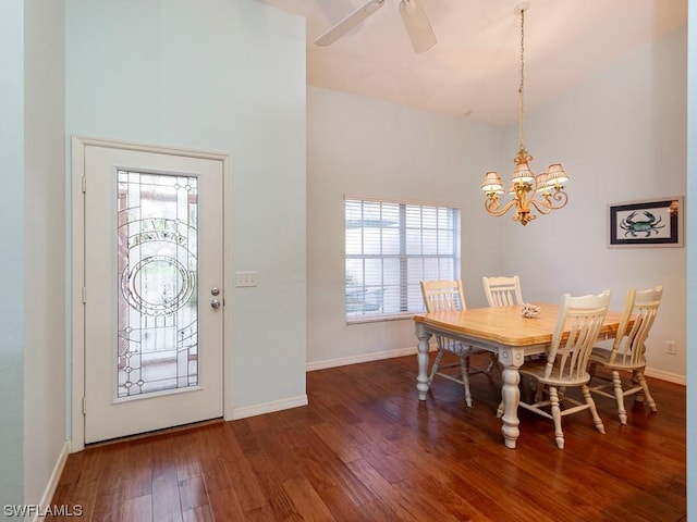 dining space with a towering ceiling, dark hardwood / wood-style floors, and ceiling fan with notable chandelier