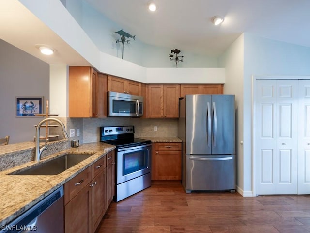 kitchen with sink, appliances with stainless steel finishes, light stone counters, tasteful backsplash, and dark hardwood / wood-style flooring