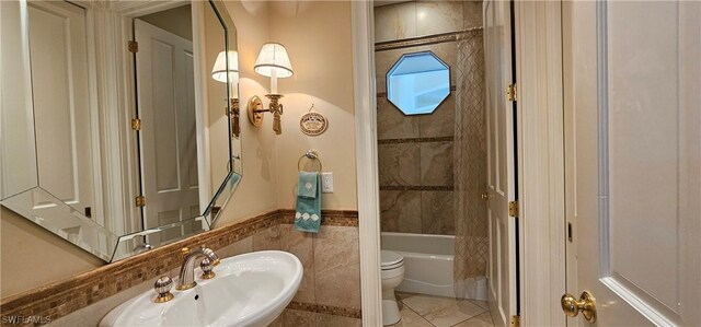 full bathroom featuring tiled shower / bath combo, toilet, tile walls, tile patterned floors, and sink