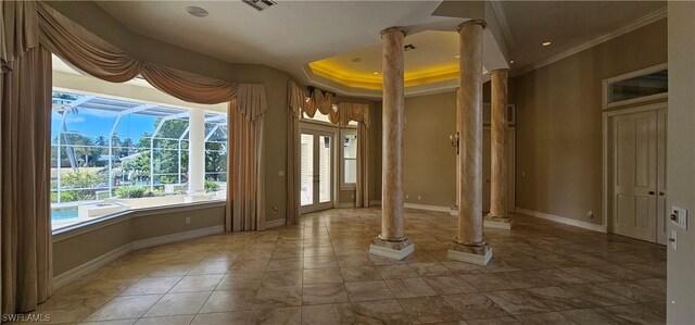 interior space featuring a tray ceiling, ornamental molding, and ornate columns