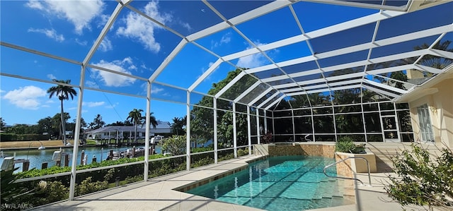 view of swimming pool with glass enclosure, a patio area, pool water feature, and a water view