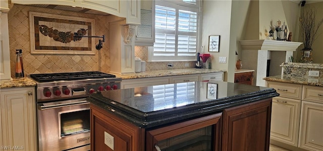 kitchen with backsplash, light stone counters, and premium range