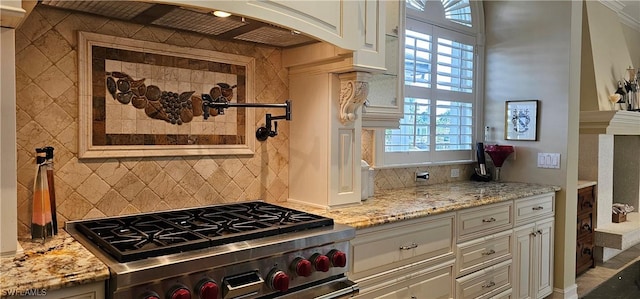 kitchen with white cabinets, high end stainless steel range, backsplash, and light stone counters