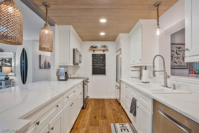 kitchen with a sink, white cabinetry, pendant lighting, and premium appliances