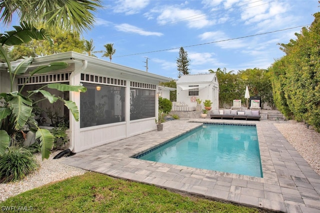 outdoor pool featuring an outbuilding, a sunroom, and a patio