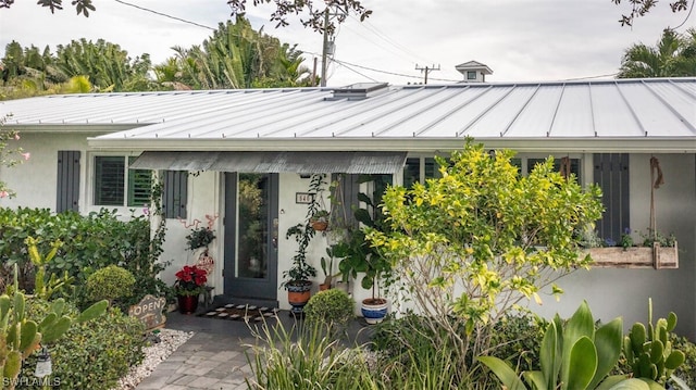 view of exterior entry with a standing seam roof, metal roof, and stucco siding