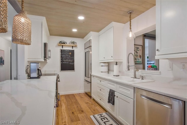 kitchen featuring light wood-style flooring, appliances with stainless steel finishes, white cabinetry, pendant lighting, and a sink