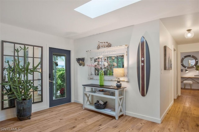 foyer entrance with a skylight, baseboards, and hardwood / wood-style floors