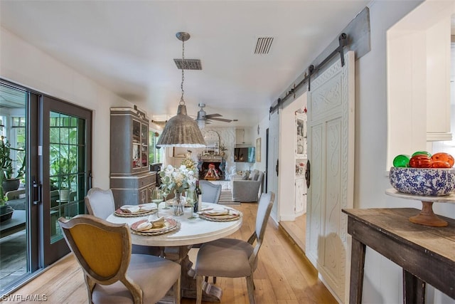 dining area featuring light wood-style floors, a barn door, and visible vents