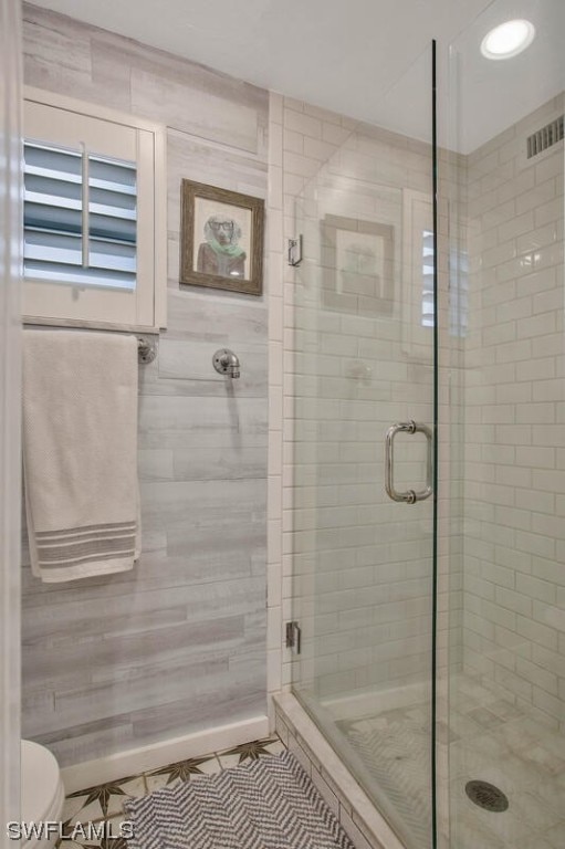 bathroom with visible vents, baseboards, toilet, tile patterned floors, and a shower stall