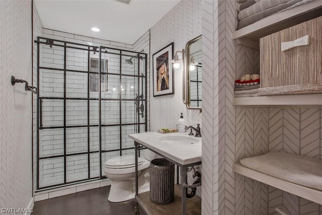 bathroom featuring visible vents, toilet, a stall shower, a sink, and wallpapered walls