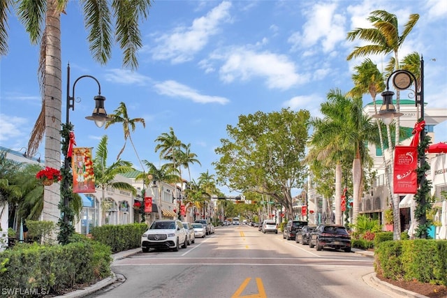 view of road featuring sidewalks, traffic lights, street lights, and curbs