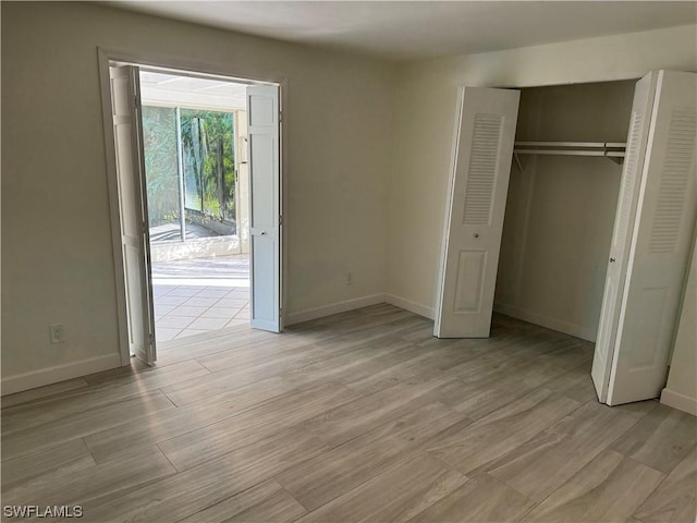 unfurnished bedroom featuring light hardwood / wood-style floors, a closet, and access to outside