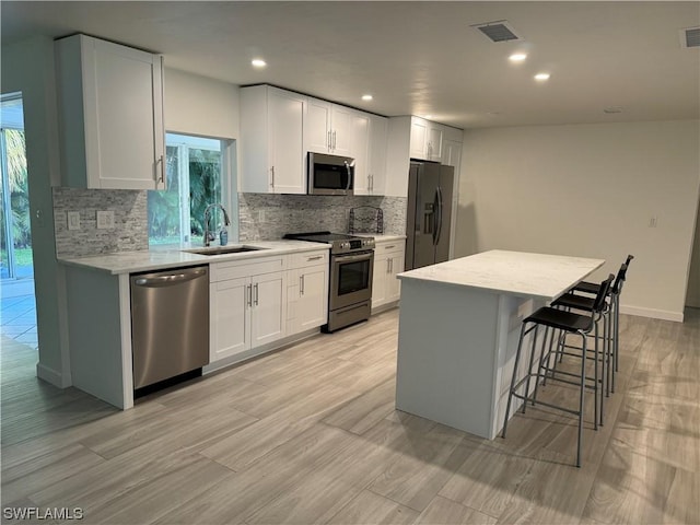 kitchen with white cabinetry, sink, a center island, and appliances with stainless steel finishes