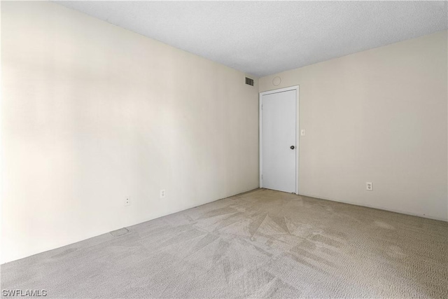 carpeted empty room featuring a textured ceiling