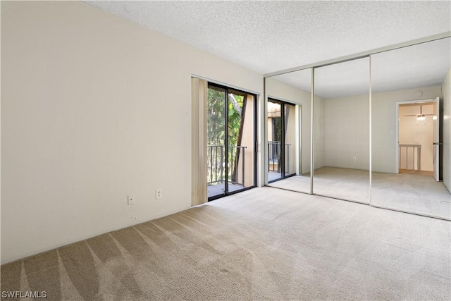 unfurnished bedroom with access to exterior, light colored carpet, a textured ceiling, and a closet