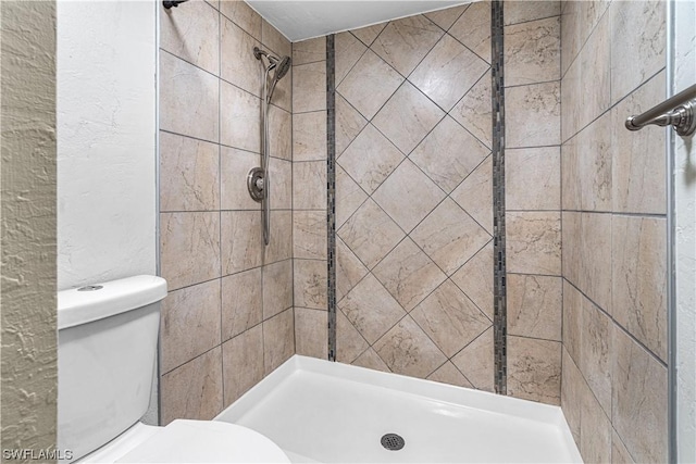 bathroom featuring tiled shower and toilet