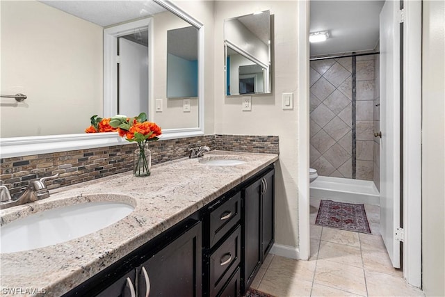 bathroom with vanity, tile patterned flooring, decorative backsplash, toilet, and a tile shower