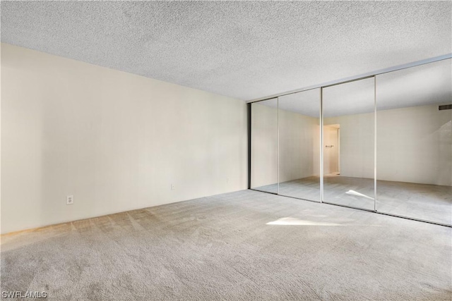 unfurnished bedroom featuring light colored carpet, a textured ceiling, and a closet