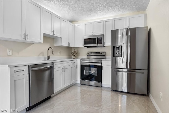 kitchen with a textured ceiling, stainless steel appliances, white cabinetry, and sink