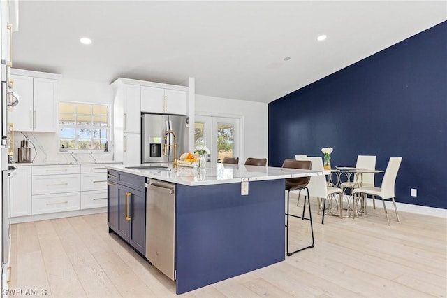 kitchen with white cabinets, appliances with stainless steel finishes, a kitchen island with sink, and a healthy amount of sunlight