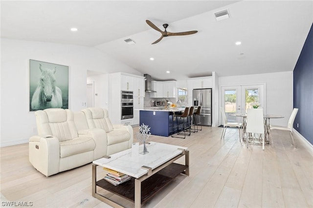 living room featuring ceiling fan, french doors, light hardwood / wood-style floors, and vaulted ceiling