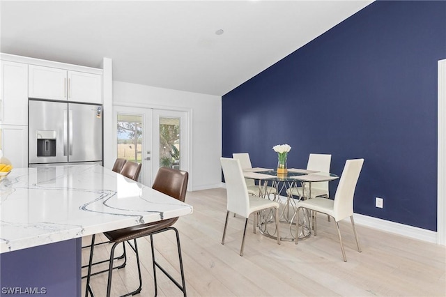 dining space featuring lofted ceiling, light hardwood / wood-style flooring, and french doors