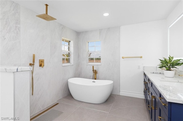 bathroom with a tub, tile patterned flooring, vanity, and tile walls