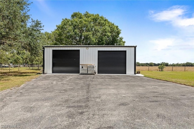 garage featuring a rural view and a yard