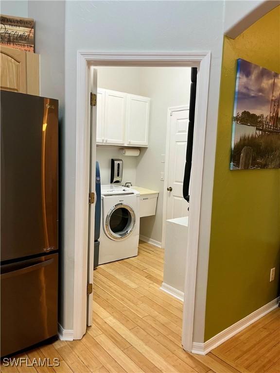 washroom featuring cabinets, washer / dryer, and light hardwood / wood-style flooring