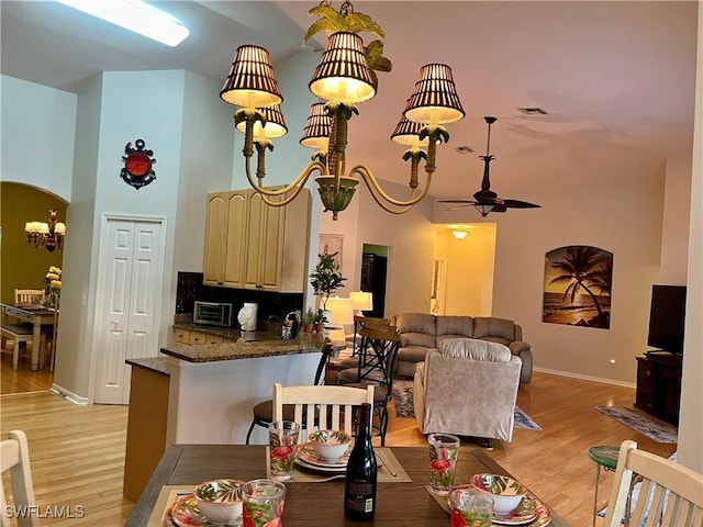 interior space featuring ceiling fan with notable chandelier, light wood-type flooring, and a towering ceiling