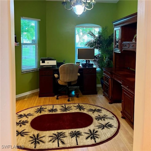 office with light wood-type flooring and an inviting chandelier