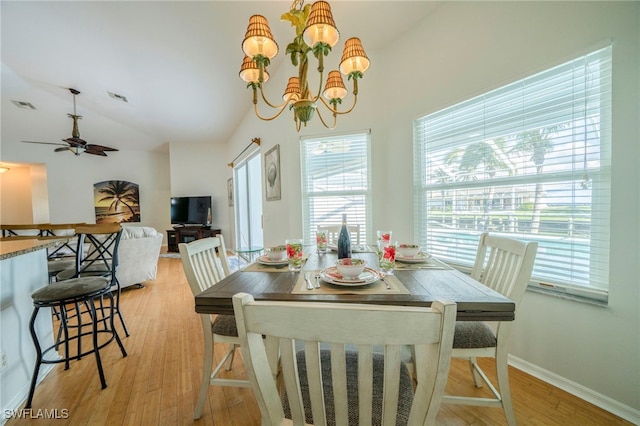 dining room with ceiling fan with notable chandelier, light hardwood / wood-style flooring, and vaulted ceiling