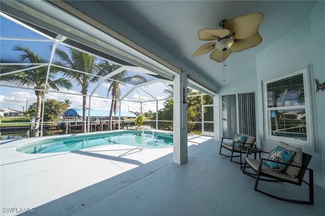 view of pool with a patio, glass enclosure, and ceiling fan