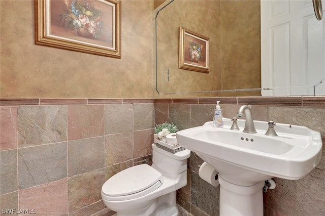 bathroom with sink, toilet, and tile walls