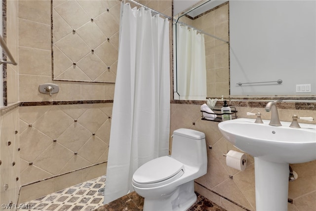 bathroom featuring a shower with shower curtain, toilet, and tile walls